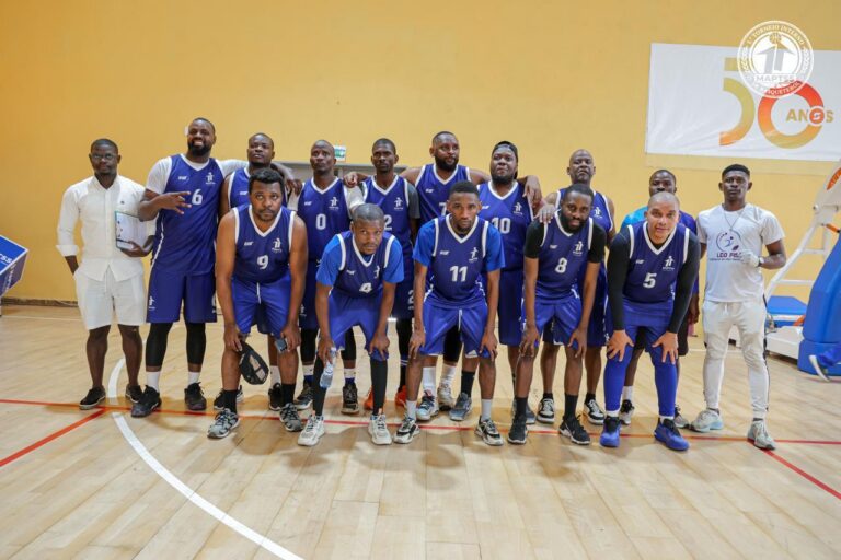 Jogadores de equipamento azul e equipa técnica posam no pavilhão